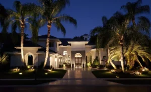 Luxury home with landscape lighting and illuminated palm trees