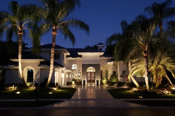 Luxury home with landscape lighting and illuminated palm trees